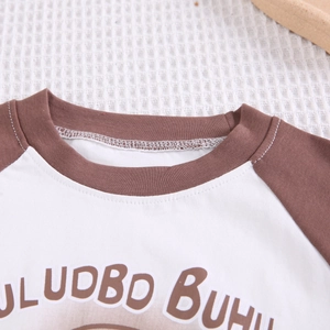 Détail du col rond côtelé et des manches raglan sur un t-shirt en coton pour enfant