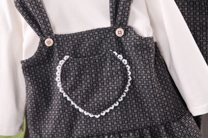 Détail de la robe à carreaux pour fille avec poche en dentelle cœur et bouton déco