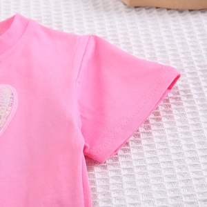 Détail de la manche d'un t-shirt en coton rose avec coutures et cœur en paillettes