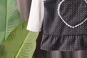 Détail de tenue pour fillette avec manches blanches et tissu à carreaux avec dentelle