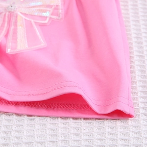 Détail macro de l'ourlet en coton rose avec nœud à paillettes et ornement en strass