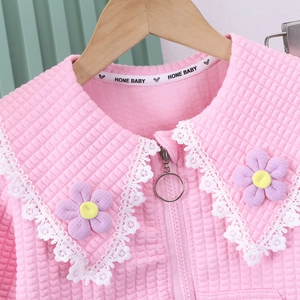 Detail of pink quilted baby jacket with lace collar and purple floral accents