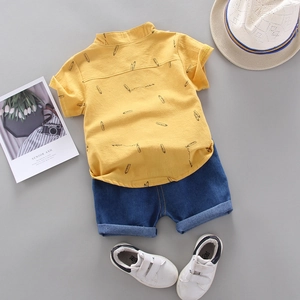 Detailed flat lay of toddler summer set with yellow pencil print shirt and denim shorts