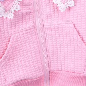 Detail of pink waffle knit jacket featuring white lace collar and zip-up front