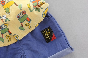 Dettaglio del set per bambini con camicia gialla con escavatore e pantaloncini blu