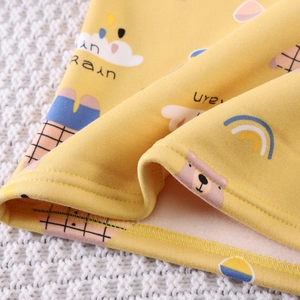 Detail of warm yellow thermal fabric with soft fleece lining and cartoon bear prints