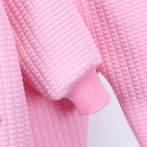 Close-up of pink waffle knit fabric and ribbed cuffs on a girls casual autumn jacket