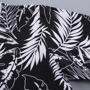 Detail shot of tropical leaf print on black short sleeve shirt showing stitching