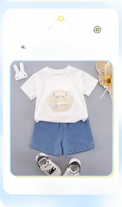 Ensemble d'été pour fille avec t-shirt blanc brodé et short en jean posé à plat sur fond gris