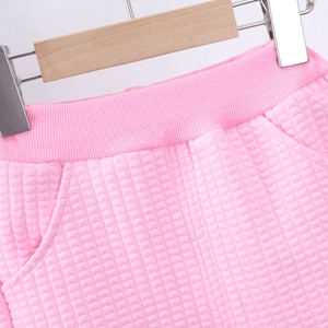 Detail of pink quilted girl's trousers featuring ribbed elastic waist and side pockets