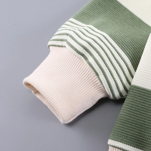 Detailed close-up of green and white striped knit sleeve with elastic ribbed pink cuff