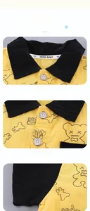 Detail of yellow toddler shirt showing black collar and silver buttons with engraved text