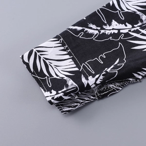 Detail of neatly stitched shirt cuff featuring black and white tropical leaf patterns
