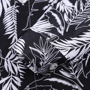 Detailed macro view of tropical leaf print fabric and white fashion button on a shirt