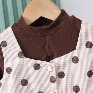 Dettaglio dell'abito a pois in velluto a coste bianco e maglia a costine marrone su gruccia