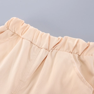 Close-up of elastic waistband and slanted pocket detail on peach cotton twill pants