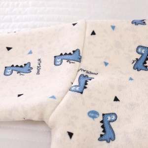 Close-up of soft coral fleece kids pajamas featuring blue dinosaur prints and neat stitching