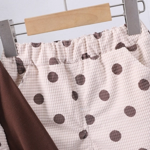 Dettaglio dei pantaloni in maglia a nido d'ape per bambina con pois marroni e elastico