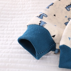 Detail of blue ribbed elastic cuffs on warm cream fleece pajamas with dinosaur print
