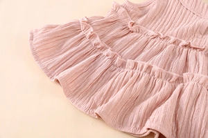 Detail of pink cotton fabric with layered ruffles and textured vertical grain on kids set