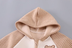 Detail of baby hoodie with plaid hood, soft fleece lining and cute bear patch