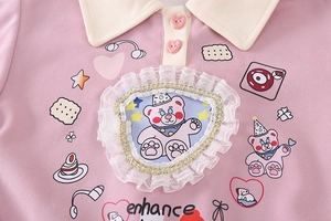 Detail of pink girls' sweatshirt featuring heart buttons and a lace bear patch