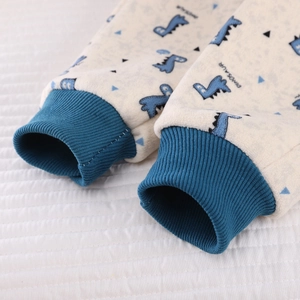 Detail of ribbed blue cuffs and soft polar fleece fabric with blue dinosaur prints