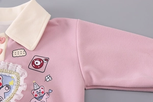 Detail of pink girls polo sweatshirt featuring lace edges and heart-shaped buttons