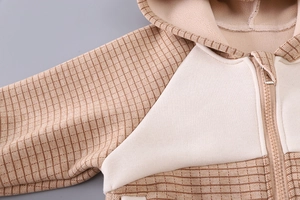 Detailed view of the thick fleece lining and brown checkered fabric on the child's jacket