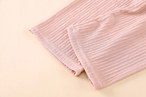 Detail of pink seersucker fabric texture and precise stitching on kids trouser cuffs