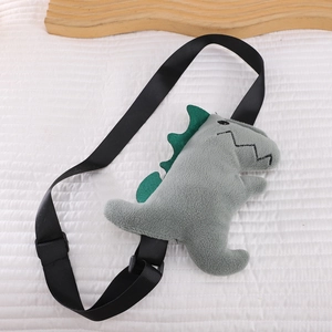 Detail of grey plush dinosaur bag with soft velvet texture and green dorsal fins