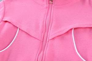 Détail d'une veste en tricot rose avec fermeture éclair et passepoil blanc sur le tissu