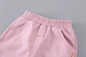 Detail of pink cotton trousers featuring elastic waistband and functional side pockets