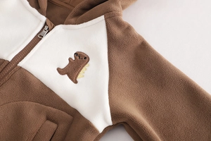 Détail d'un sweat à capuche d'hiver épais avec broderie dinosaure et texture polaire douce