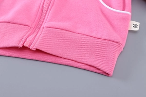 Vue détaillée du sweat à capuche rose montrant l'ourlet côtelé et l'étiquette de taille 80