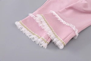 Detailed view of pink girls' trousers with white lace ruffles and gold sequin embroidery