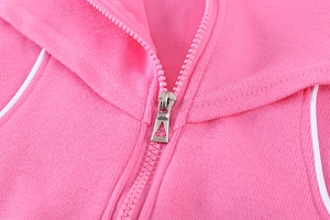Détail de la veste en maille rose montrant la fermeture éclair et le liseré blanc
