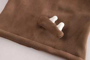 Vue détaillée de la capuche en peluche marron avec oreilles à pompons blancs et polaire douce