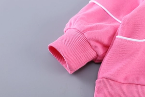 Gros plan sur un sweat à capuche rose pour fille avec passepoil blanc et poignets côtelés