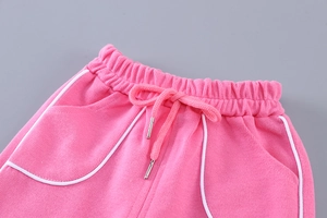 Détail du jogging en coton rose avec cordon élastique et bordure passepoilée blanche
