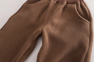 Détail d'un pantalon en polaire marron avec taille élastique et texture douce pour garçon