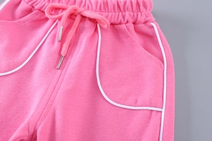 Détail du pantalon de sport rose en maille avec taille élastique, cordon et liseré blanc