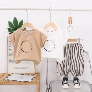 Détail du t-shirt imprimé et du short rayé pour fille sur un cintre en bois naturel