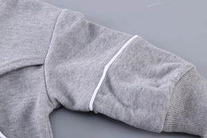Détail du tissu en maille grise avec des accents rayés et des poignets côtelés