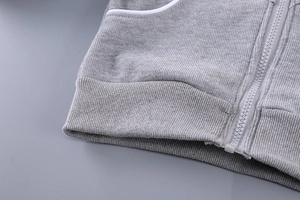 Détail de la veste grise pour fille montrant la fermeture éclair et l'ourlet côtelé