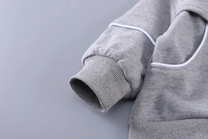 Gros plan d'un sweat-shirt gris avec des poignets côtelés et des passepoils blancs