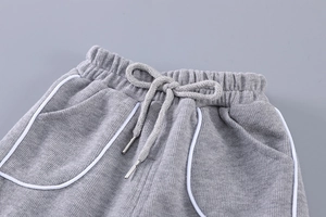 Détail du jogging gris avec taille élastique, cordon de serrage et liseré blanc