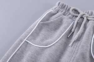 Détail du pantalon en tricot gris pour enfant avec taille élastique à cordon et passepoils
