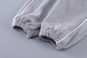 Détail du poignet du survêtement en tricot gris foncé avec liseré blanc et bord élastique