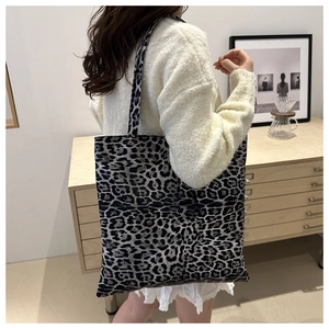 Détail d'un sac cabas en toile à imprimé léopard porté par un mannequin en intérieur
